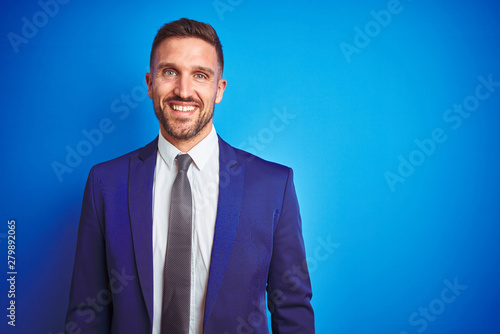 Young handsome business man over blue isolated background with a happy and cool smile on face. Lucky person.