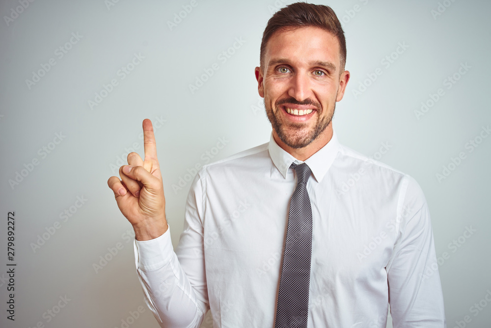 Young handsome business man wearing elegant white shirt over isolated background with a big smile on face, pointing with hand and finger to the side looking at the camera. Young handsome business man wearing elegant white shirt over isolated background with a big smile on face, pointing with hand and finger to the side looking at the camera.