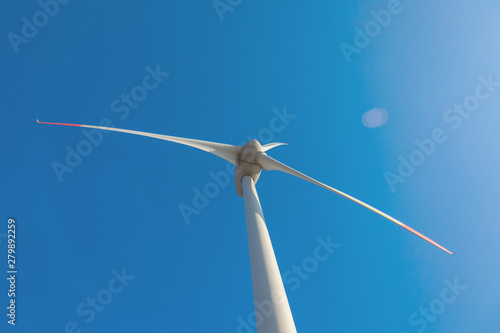 wind turbine with sun flare blue sky background view from below