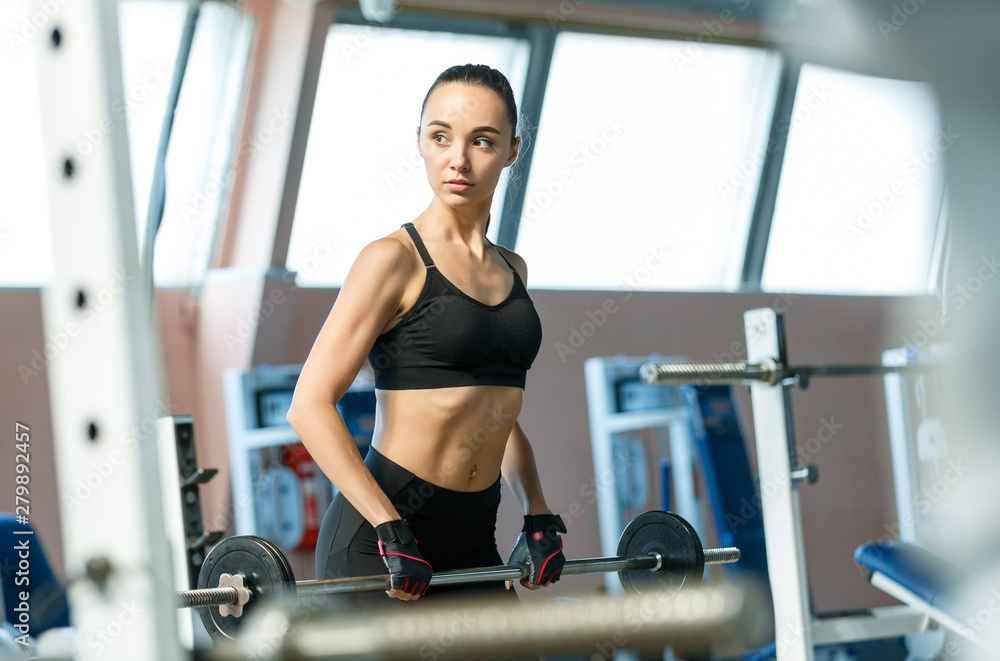 Woman in a gym exercises with a barbell Woman in a gym exercises with a barbell