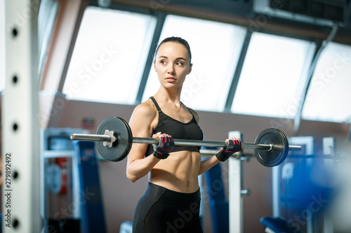 Woman in a gym exercises with a barbell