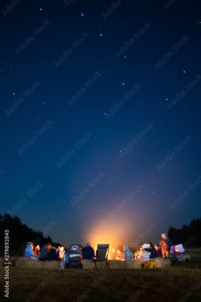 Bonfire in the summer camp with blurred people around it