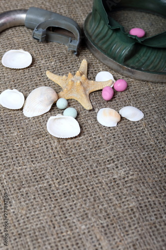 Starfish, shells and colored pebbles. Mask with a snorkel for scuba diving. They lie on a rough linen fabric.