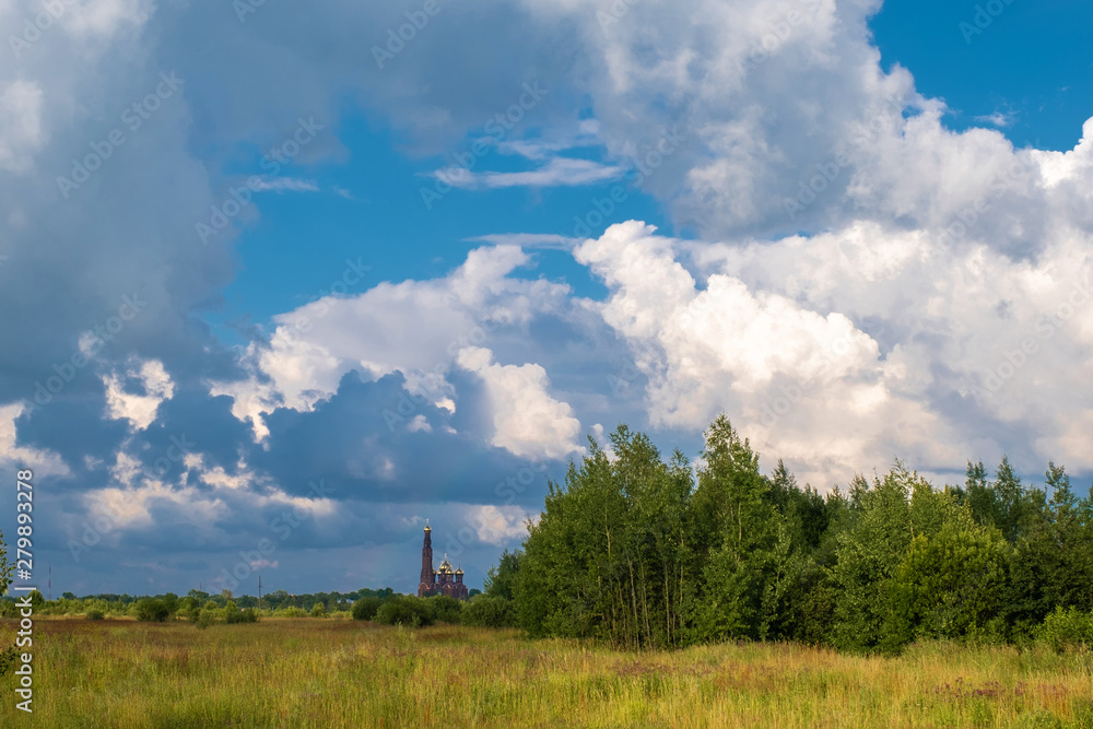 Bright landscape with cumulus clouds and a red church with a bell tower. Bright landscape with cumulus clouds and a red church with a bell tower.