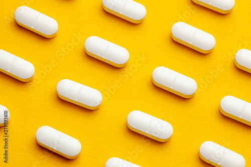 White pills on yellow background.