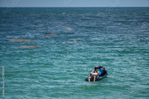 Man stranded on a wave runner in the ocean waiting for rescue to arrive
