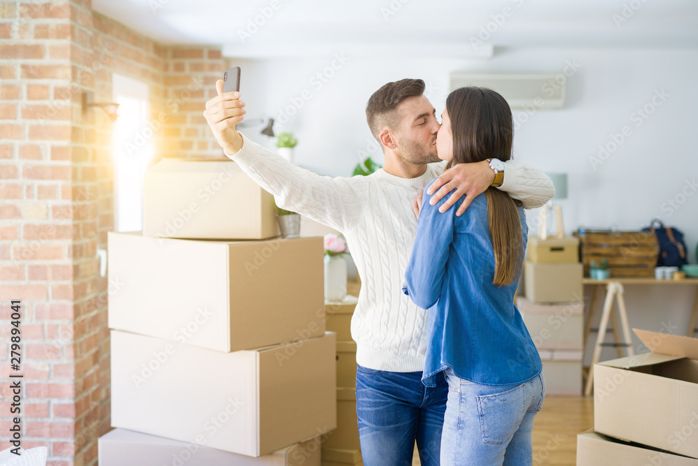 Beautiful couple taking a selfie photo using smartphone at new apartment, smiling happy for new house Beautiful couple taking a selfie photo using smartphone at new apartment, smiling happy for new house