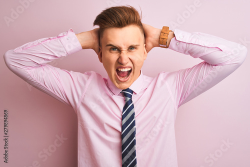 Young handsome businessman wearing shirt and tie standing over isolated pink background Crazy and scared with hands on head, afraid and surprised of shock with open mouth