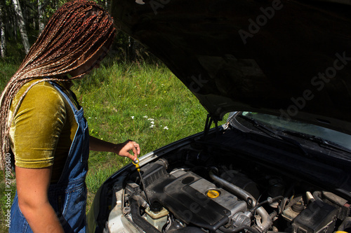 young girl checks the oil in the car engine
