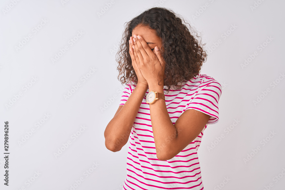 Young brazilian woman wearing pink striped t-shirt standing over isolated white background with sad expression covering face with hands while crying. Depression concept. Young brazilian woman wearing pink striped t-shirt standing over isolated white background with sad expression covering face with hands while crying. Depression concept.