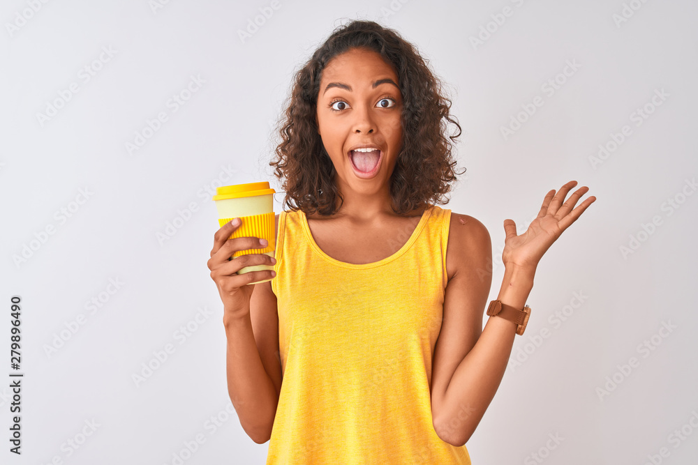 Young brazilian woman drinking take away coffee standing over isolated white background very happy and excited, winner expression celebrating victory screaming with big smile and raised hands Young brazilian woman drinking take away coffee standing over isolated white background very happy and excited, winner expression celebrating victory screaming with big smile and raised hands