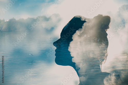 Silhouette of young woman head on background of clouds and birds