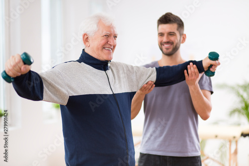 Senior man after stroke at nursing home exercising with professional physiotherapist