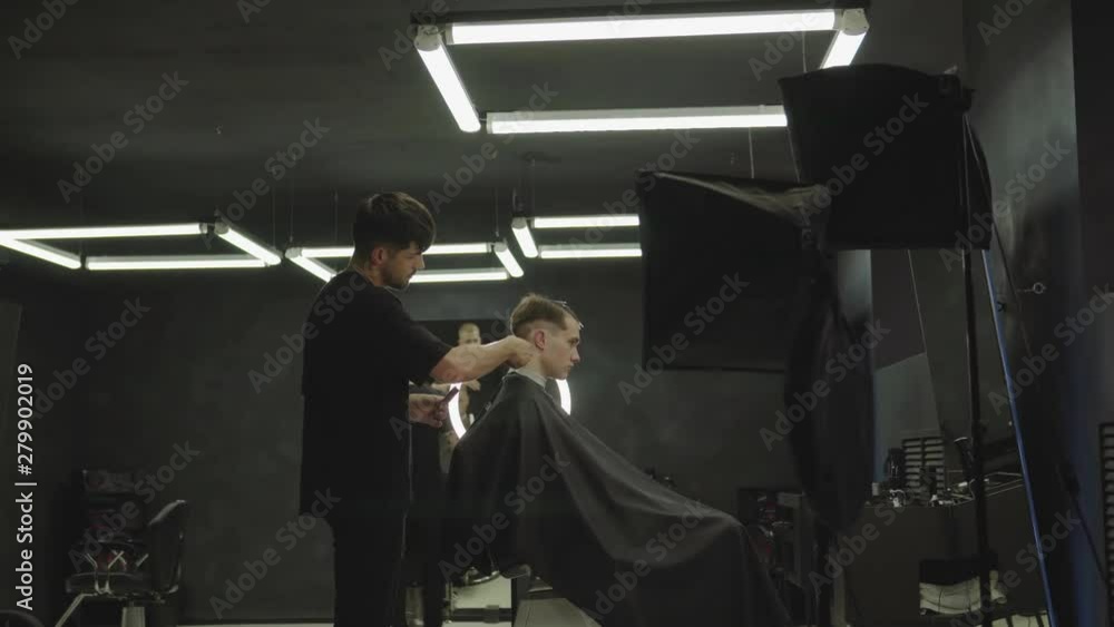 Male haircut with electric razor. Barber makes haircut for client at