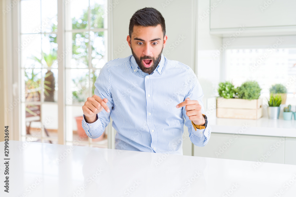 Handsome hispanic business man Pointing down with fingers showing advertisement, surprised face and open mouth Handsome hispanic business man Pointing down with fingers showing advertisement, surprised face and open mouth