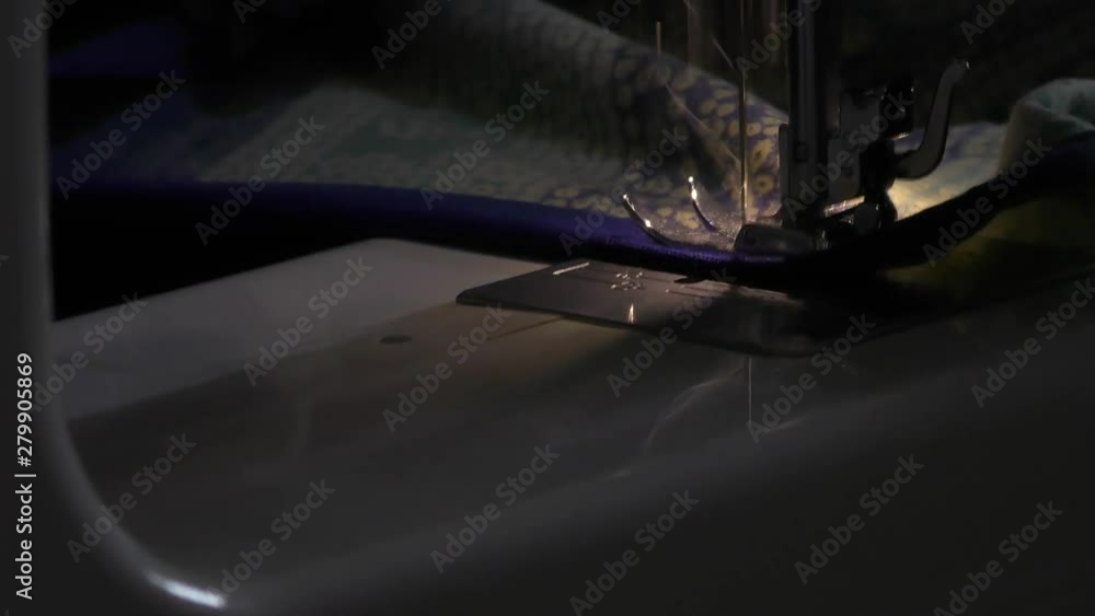 A shining sewing machine being used by a woman for stitching A shining sewing machine being used by a woman for stitching