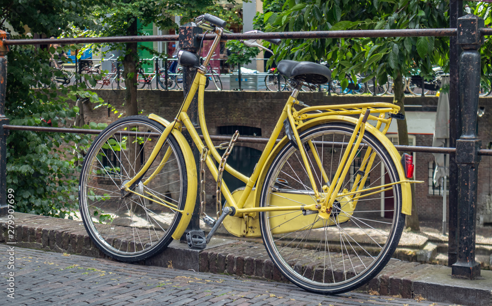 Yellow bike color locked on a river canal rail in Utrecht city, Netherlands