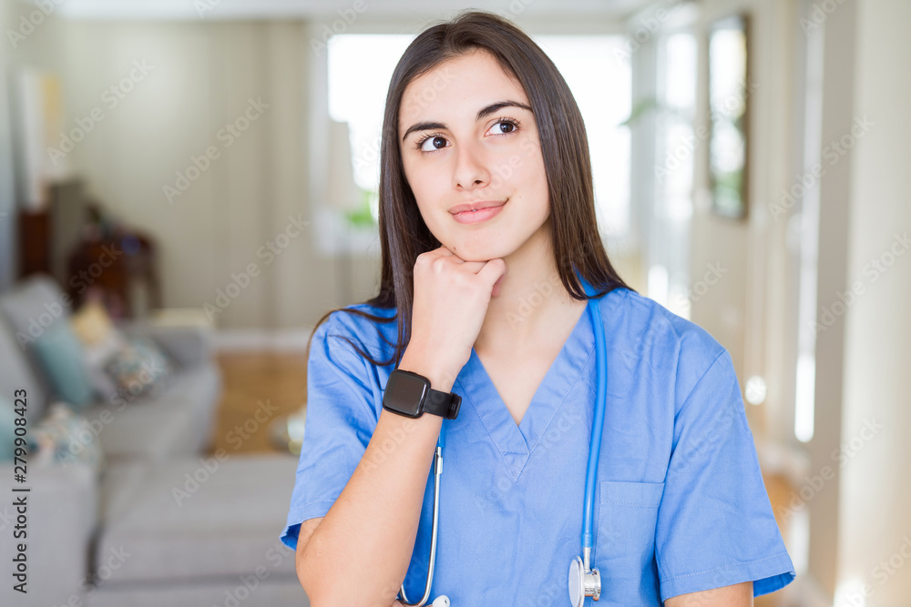 Beautiful young nurse woman wearing uniform and stethoscope at the clinic with hand on chin thinking about question, pensive expression. Smiling with thoughtful face. Doubt concept. Beautiful young nurse woman wearing uniform and stethoscope at the clinic with hand on chin thinking about question, pensive expression. Smiling with thoughtful face. Doubt concept.