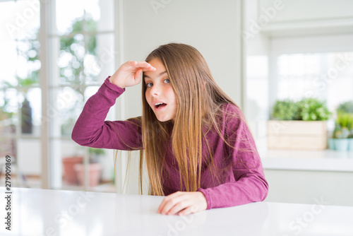 Beautiful young girl kid on white table very happy and smiling looking far away with hand over head. Searching concept. Free Download Beautiful young girl kid on white table very happy and smiling looking far away with hand over head. Searching concept. - GFXLoad