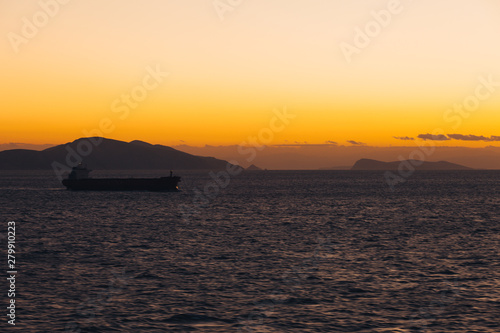 Ship sailing at sunset with island silhouette background and colorful sky