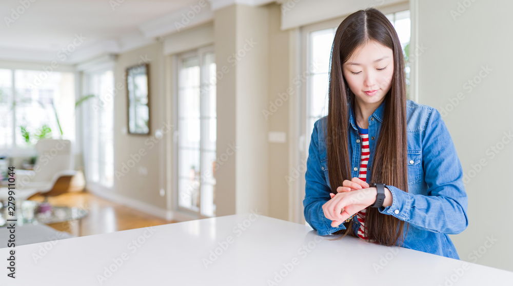Young beautiful asian woman with long hair wearing denim jacket Checking the time on wrist watch, relaxed and confident Young beautiful asian woman with long hair wearing denim jacket Checking the time on wrist watch, relaxed and confident
