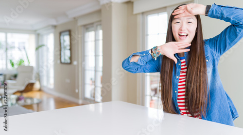 Young beautiful asian woman with long hair wearing denim jacket Smiling cheerful playing peek a boo with hands showing face. Surprised and exited