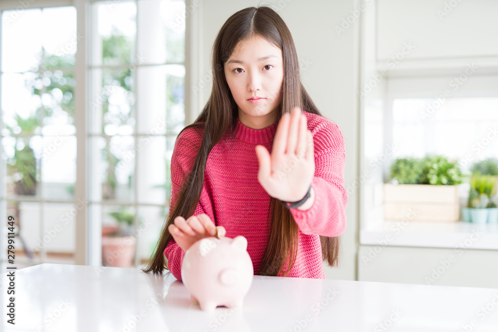 Beautiful Asian woman putting a coin inside piggy bag with open hand ...