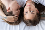 top view of two lesbians embracing while lying on bed