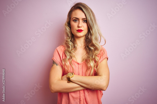 Young beautiful woman wearing t-shirt standing over pink isolated background skeptic and nervous, disapproving expression on face with crossed arms. Negative person.