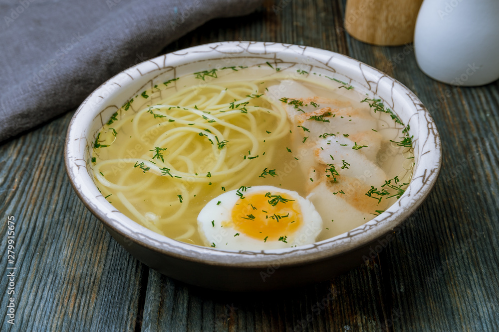Chicken soup bouillon in a plate on blue wood table Chicken soup bouillon in a plate on blue wood table