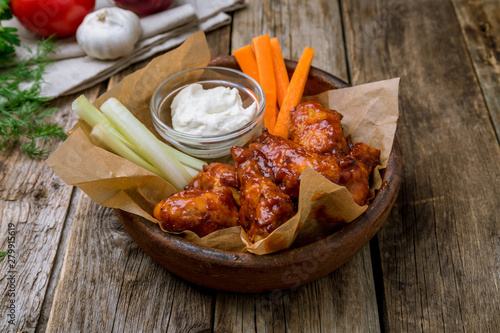 chicken wings in barbecue sauce with blue cheese sause on wooden table