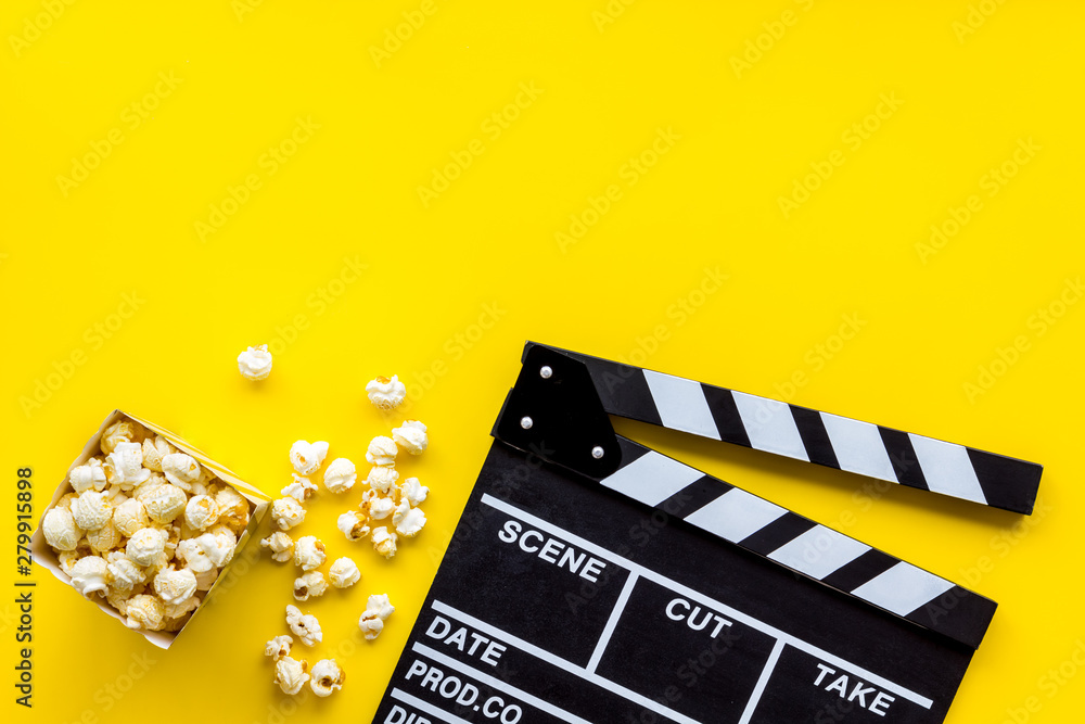 Watch film in cinema with popcorn and clapperboard on yellow background top view