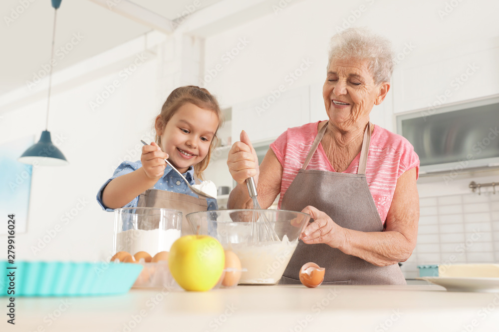 Cute girl and her grandmother cooking in kitchen Cute girl and her grandmother cooking in kitchen