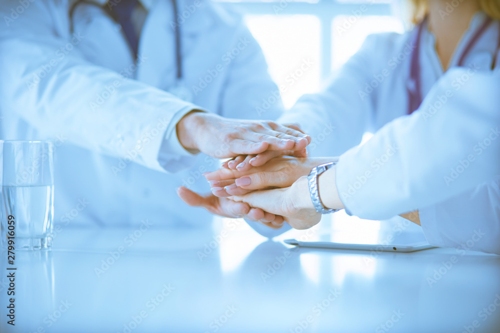 Team of doctors putting hands together, closeup Team of doctors putting hands together, closeup