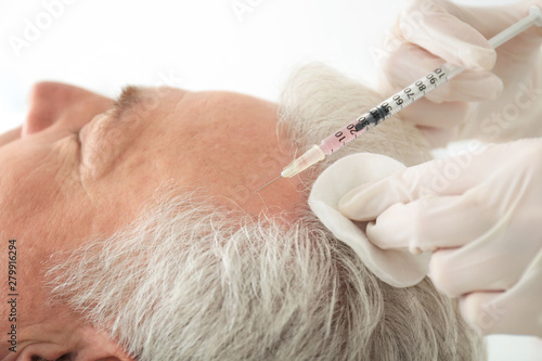 Senior man with hair loss problem receiving injection in salon, closeup