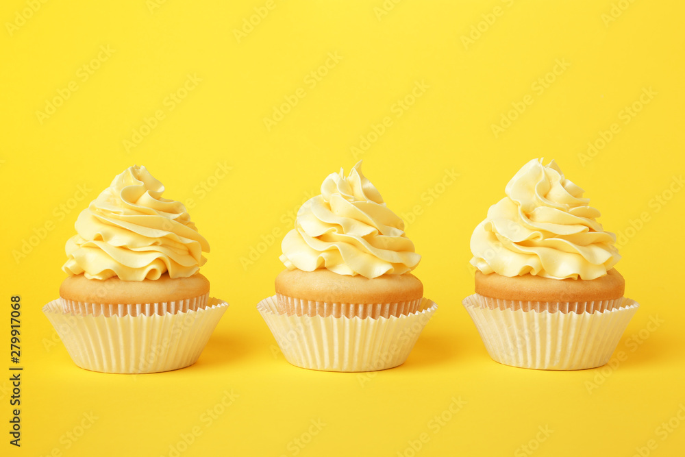 Tasty cupcakes with cream on yellow background
