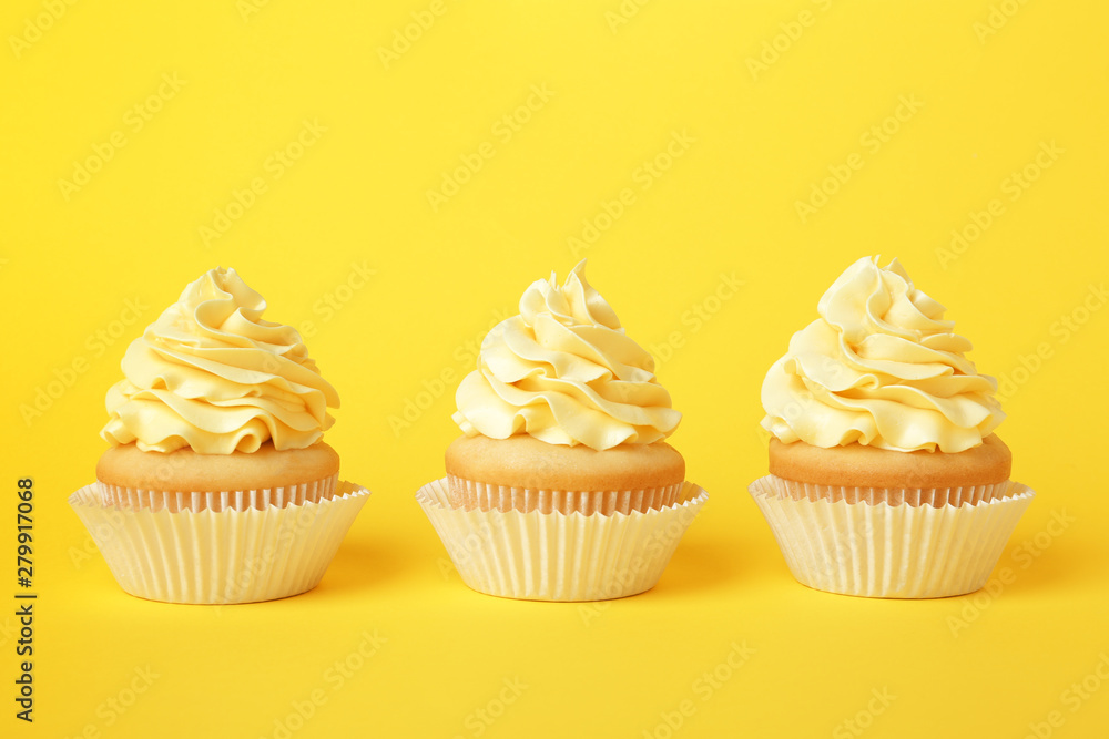 Tasty cupcakes with cream on yellow background Tasty cupcakes with cream on yellow background