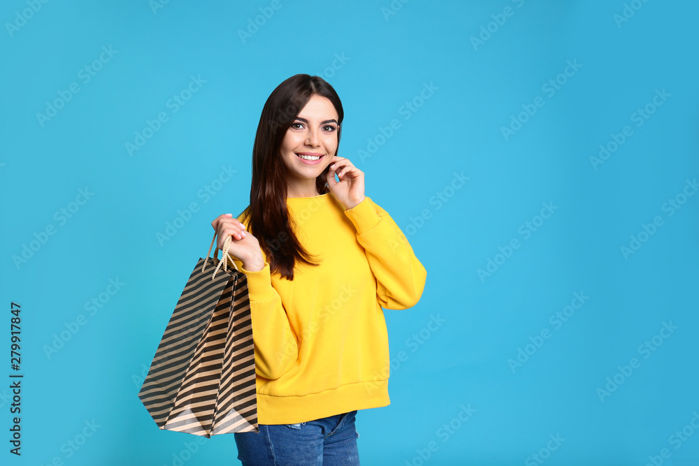 Portrait of young woman with paper bags on blue background Portrait of young woman with paper bags on blue background