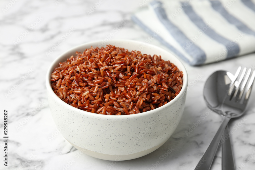 Bowl with delicious cooked brown rice on white marble table Bowl with delicious cooked brown rice on white marble table