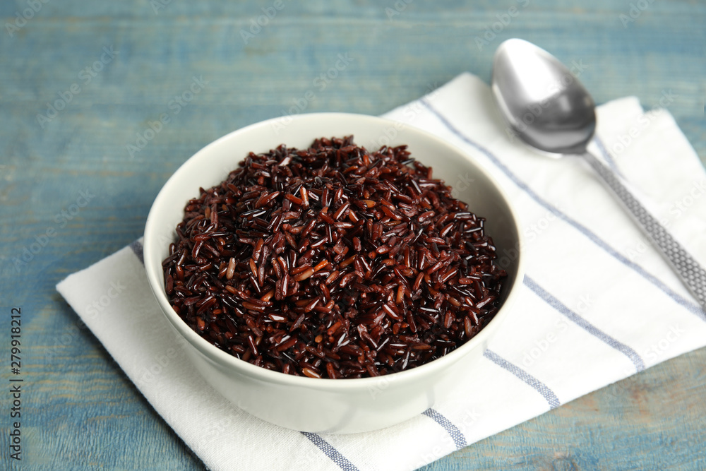 Bowl with delicious cooked brown rice on color wooden table Bowl with delicious cooked brown rice on color wooden table
