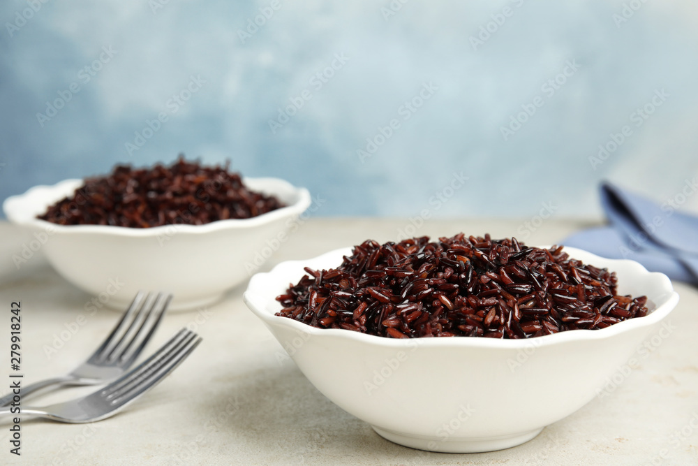 Bowls with delicious cooked brown rice on white table Bowls with delicious cooked brown rice on white table