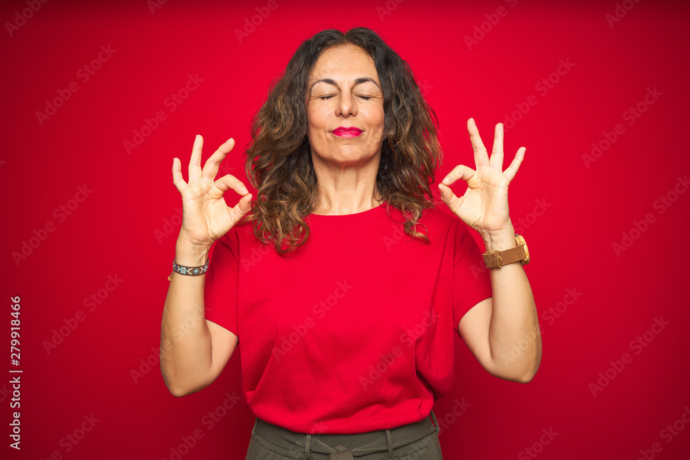 Middle age senior woman with curly hair over red isolated background relax and smiling with eyes closed doing meditation gesture with fingers. Yoga concept. Middle age senior woman with curly hair over red isolated background relax and smiling with eyes closed doing meditation gesture with fingers. Yoga concept.