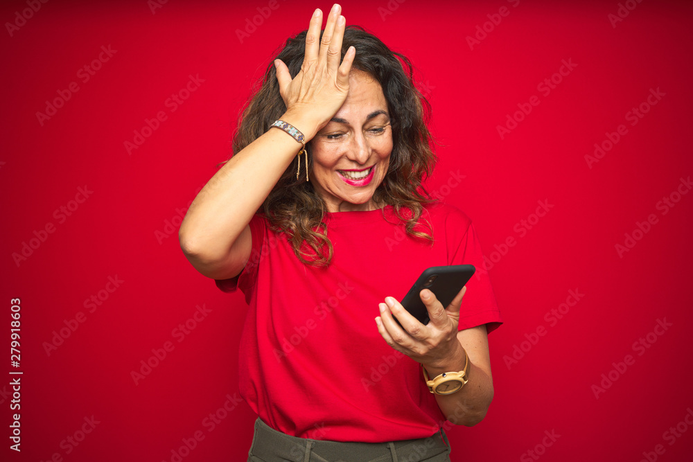 Naklejka premium Middle age senior woman using smartphone over red isolated background stressed with hand on head, shocked with shame and surprise face, angry and frustrated. Fear and upset for mistake.