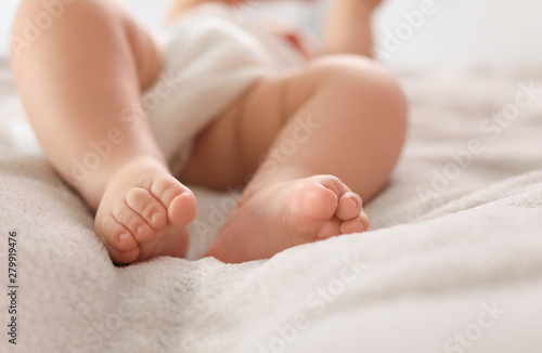 Cute little baby lying on bed, closeup of legs