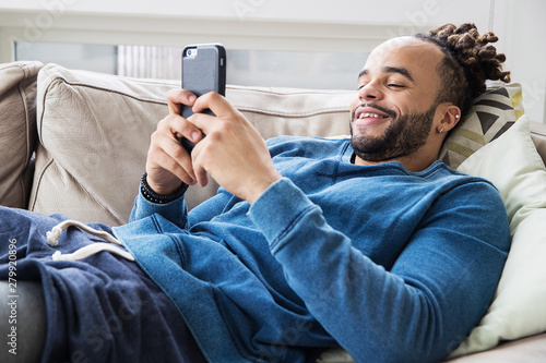 Canvas-taulu Handsome man with dreadlocks looking at his phone