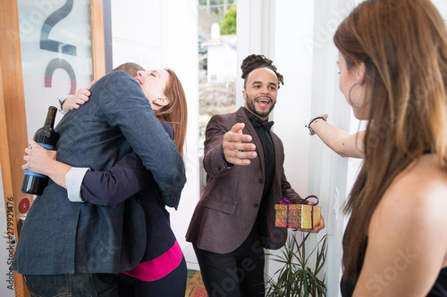 Group of friends greeting each other at door of home photo