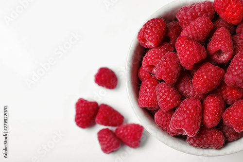 Top view of bowl with delicious ripe raspberries on white background, closeup