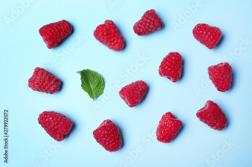 Flat lay composition with delicious ripe raspberries on blue background