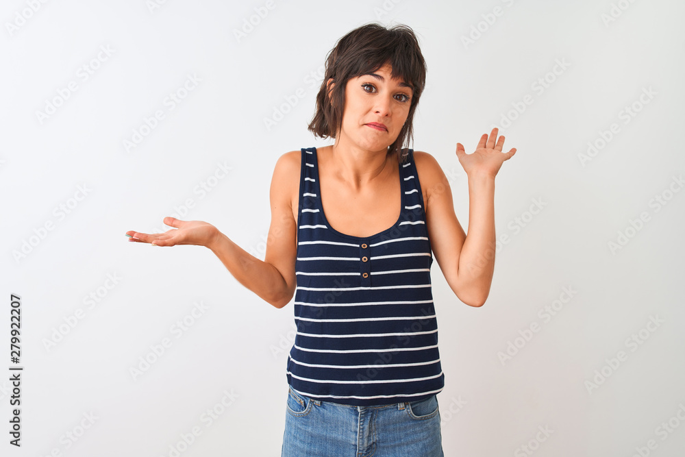 Young beautiful woman wearing striped t-shirt standing over isolated white background clueless and confused expression with arms and hands raised. Doubt concept. Young beautiful woman wearing striped t-shirt standing over isolated white background clueless and confused expression with arms and hands raised. Doubt concept.