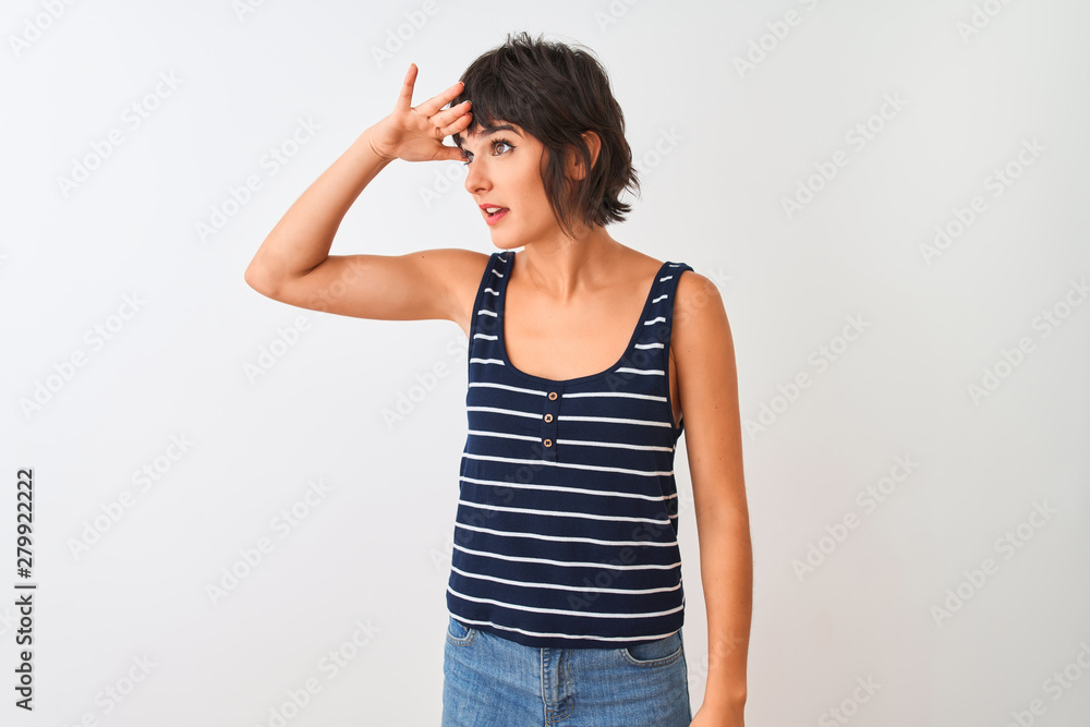 Young beautiful woman wearing striped t-shirt standing over isolated white background very happy and smiling looking far away with hand over head. Searching concept. Young beautiful woman wearing striped t-shirt standing over isolated white background very happy and smiling looking far away with hand over head. Searching concept.